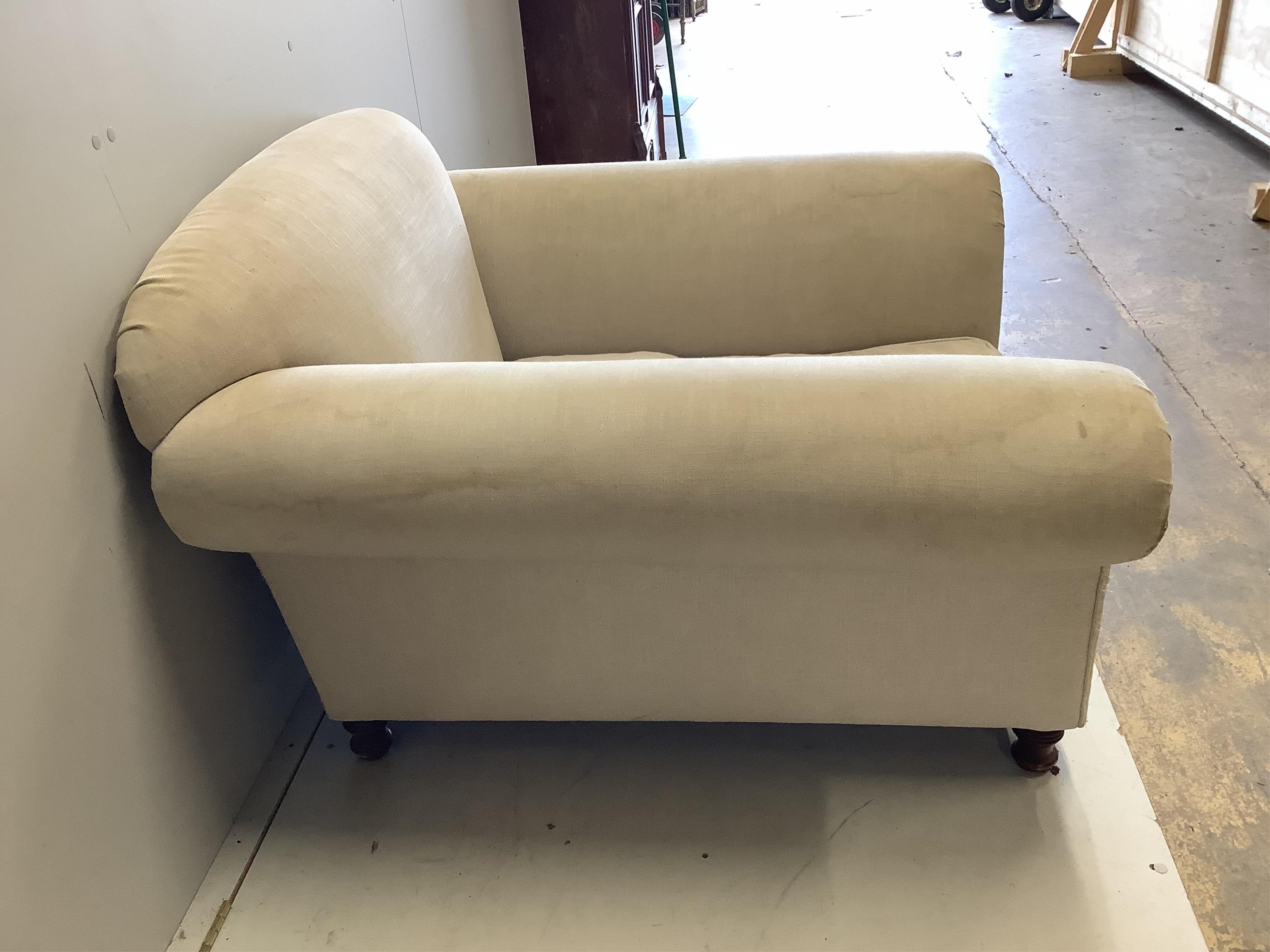 A Howard style upholstered armchair, width 115cm, depth 110cm, height 78cm. Condition - fair, upholstery scratched and requires cleaning